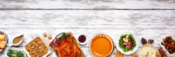 Classic Thanksgiving turkey dinner. Above view bottom border on a rustic white wood banner background. Classic Thanksgiving turkey dinner. Above view bottom border on a rustic white wood banner background with copy space. Turkey, mashed potatoes, stuffing, pumpkin pie and sides. side dish stock pictures, royalty-free photos & images