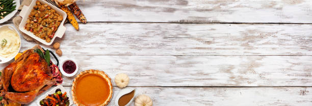 istock Traditional Thanksgiving turkey dinner. Top view corner border on a rustic white wood banner background. 1280059344