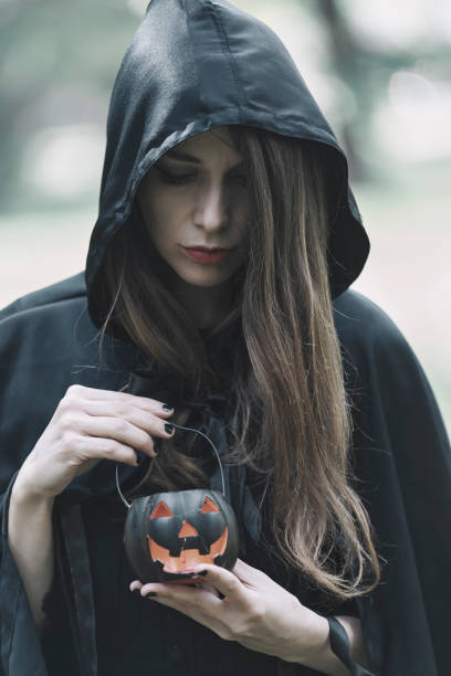 istock Witch preparing for a ritual in the forest, holding a pumpkin lantern 1280061423