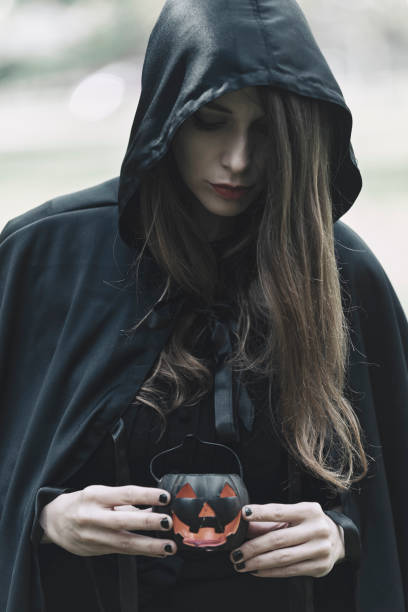 istock Witch preparing for a ritual in the forest, holding a pumpkin lantern 1280061444