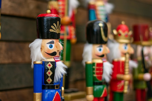 A Blue Nutcracker on a Dark Wooden Shelf With Other Nutcrackers In Line Next to It