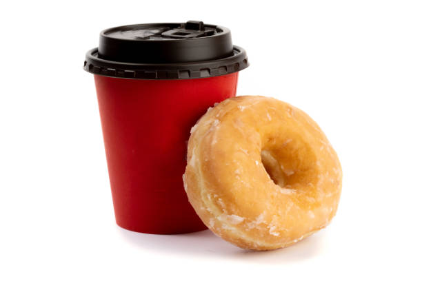 istock a sugar glazed donut resting against a red takeout coffee cup isolated on white 1280065024