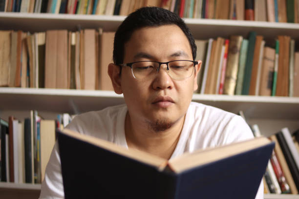istock Asian man reading book in library, educational concept. Happy smiling expression doing leisure activity 1280069683
