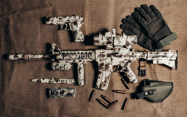 istock Camouflaged military AR-15 rifle with scope laying with knife. 1280069701
