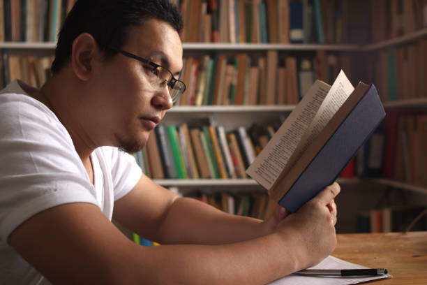 istock Asian man reading book in library, educational concept. Happy smiling expression doing leisure activity 1280069816