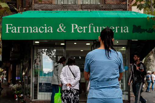 Buenos Aires, Argentina - March 19, 2020: Nurse lines up at the door of a pharmacy during the start of mandatory social isolation (quarantine) in Argentina