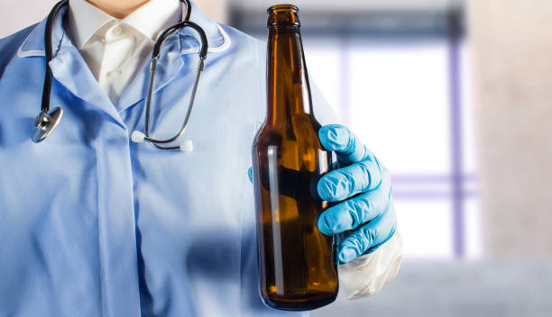 Doctor in uniform holding a beer bottle. stock photo