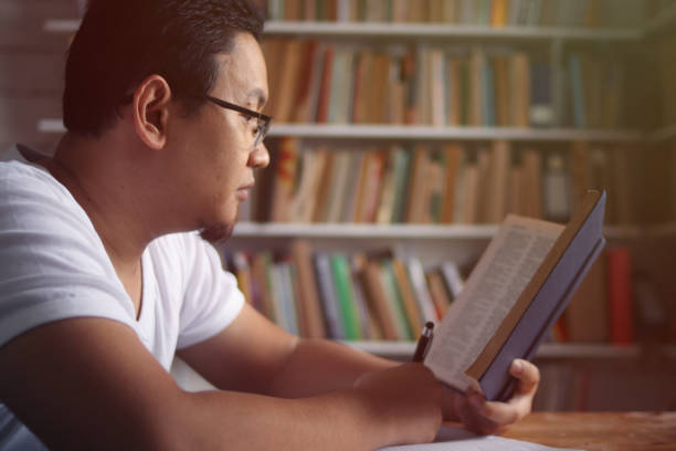 istock Asian man reading book in library, educational concept. Happy smiling expression doing leisure activity 1280069948