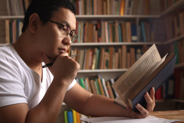 istock Asian man reading book in library, educational concept. Happy smiling expression doing leisure activity 1280070568
