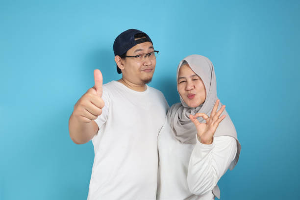 Happy Asian Muslim Couple Shows Thumbs Up Portrait of happy Asian muslim couple smiling and shows thumbs up gesture, husband and wife hugging full of love, family concept malay couple stock pictures, royalty-free photos & images