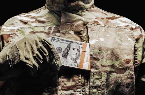Soldier in camouflage and tactical gloves putting money. stock photo