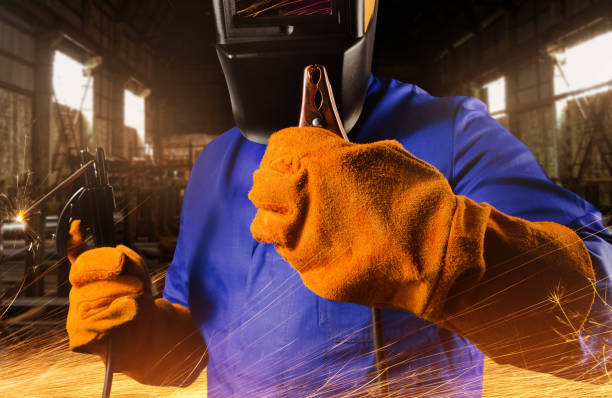 istock Welder in uniform, helmet and gloves holding electrode. 1280072032