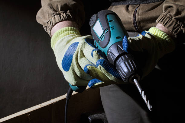 istock Worker in outfit with blue gloves holding electric drill. 1280072574