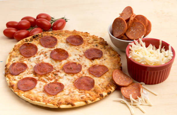 istock a pepperoni pizza on a wooden board surrounded by pepperoni cheese and tomatoes 1280072673
