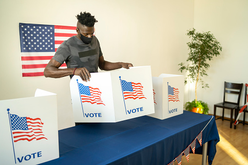 Young afro-American man helping with preparation the voting booths for Election Day