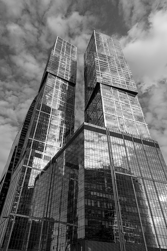 Skyscrapers, business office buildings in commercial district, modern architecture with cloudy sky on background, monochrome shot