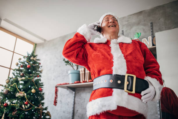 istock Man dressed like Santa Claus talking on mobile phone at home 1280078684