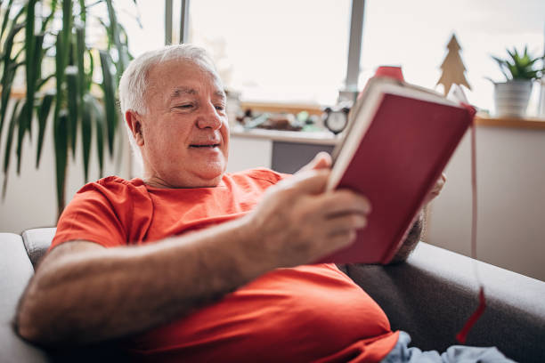 istock Senior man reading a book at home 1280079414