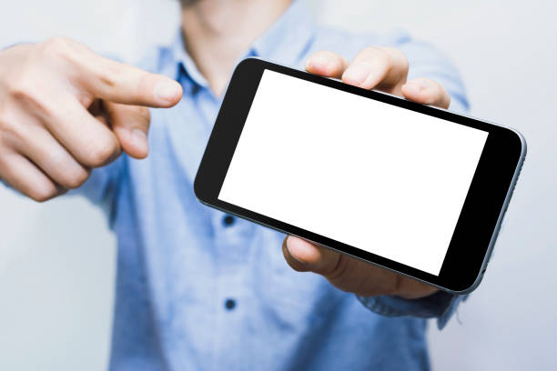 istock A man pointing at a black mobile phone with a blank white desktop screen. 1280080541