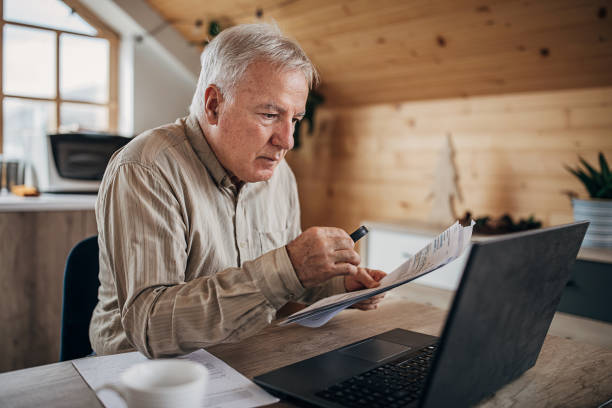 istock Senior man reading a document with the help of a magnifying glass at home 1280081251