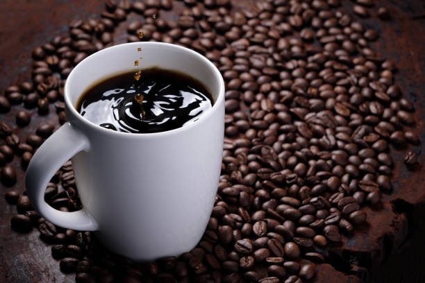 istock coffee droplets drop on black coffee water in white mug with surrounded by roasted coffee beans on dark red wood table 1280093459