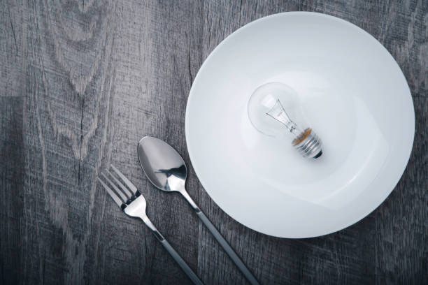 istock the vintage light bulb above a white dish decoration with stainless steel spoon and fork on a grey wooden table, for creative idea concept design 1280094319