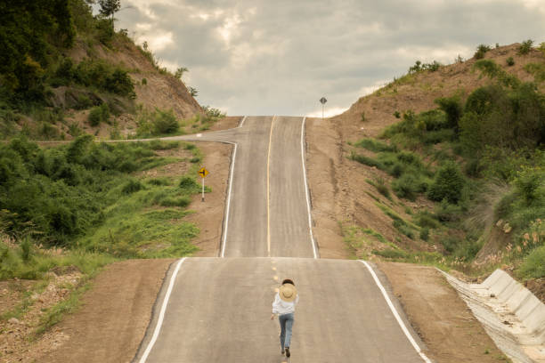 istock Woman alone in beautiful empty rural curve, asphalt road way. 1280096525