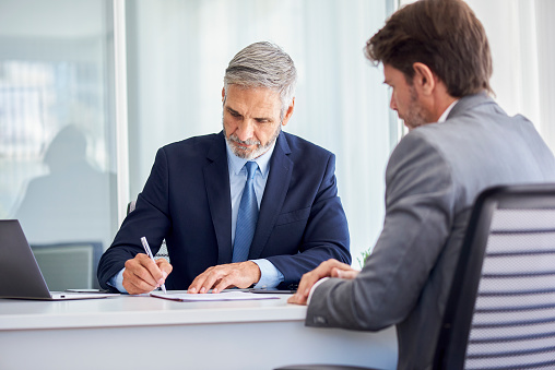 Mature businessman signing documents in office