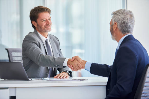 istock Businessmen shaking hands in office 1280097873