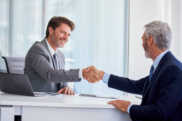 istock Businessmen shaking hands in office 1280097895