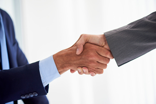 Close-up of two businessmen shaking hands in office