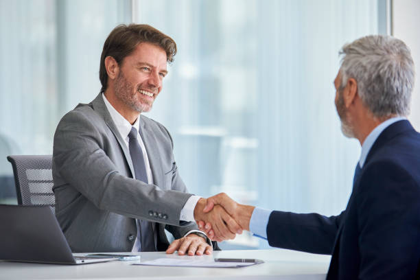 istock Businessmen shaking hands in office 1280097903
