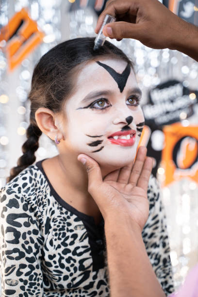 istock Parent helping her daughter to get ready for Halloween by doing make-up - concept of Halloween, holiday and childhood festival celebration and preparation. 1280098730