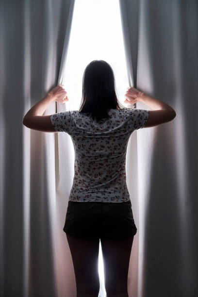istock Woman drawing curtains at home 1280098965