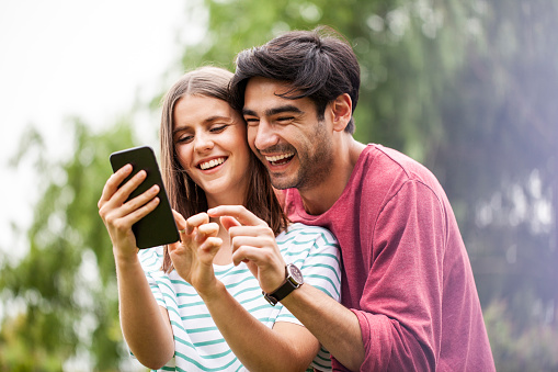 Smiling young couple using smart phone outdoors