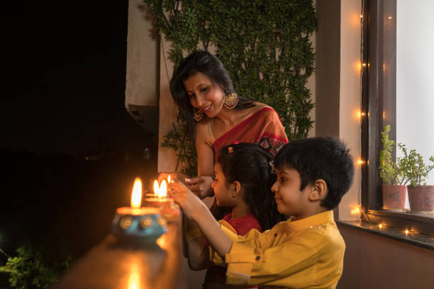 Mother with children in house balcony lighting diyas Mother with children in house balcony lighting diyas diwali photos stock pictures, royalty-free photos & images