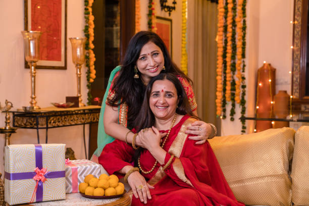 Mother and daughter in law in smiling portrait pose Mother and daughter in law in tradional wear sitting in coach  in smiling portrait pose diwali photos stock pictures, royalty-free photos & images