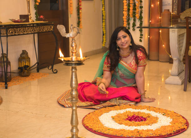 istock Lady in ethnic wear sitting on floor besides rangoli 1280100220
