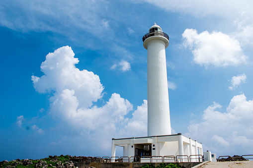 Cape Zanpa Lighthouse, Okinawa, Japan with surrounding volcanic rock formation and blue sky