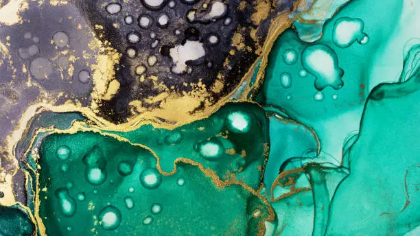 Photo of Closeup of green, black and shiny golden alcohol ink abstract texture, trendy wallpaper.