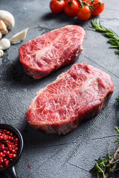 istock Raw top blade flat Ironcut, on black slate , bio marbled beef  with herbs tomatoes peppercorns over grey stone surface background side vertical close up 1280106814