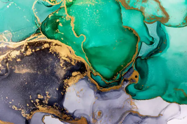 Photo of Closeup of green, black and shiny golden alcohol ink abstract texture, trendy wallpaper.