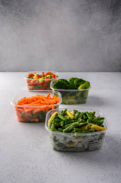 istock Frozen vegetables carrot, broccoli, spinach, green pods beans in plastic trays on gray background, close up 1280107504