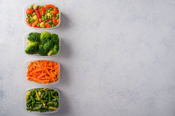 istock Frozen vegetables mix carrot, broccoli, green pods beans in plastic trays on light background, top view 1280107855