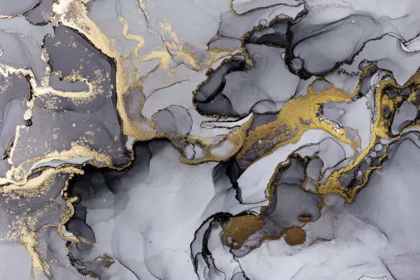 Photo of Closeup of black and shiny golden alcohol ink abstract texture, trendy wallpaper.