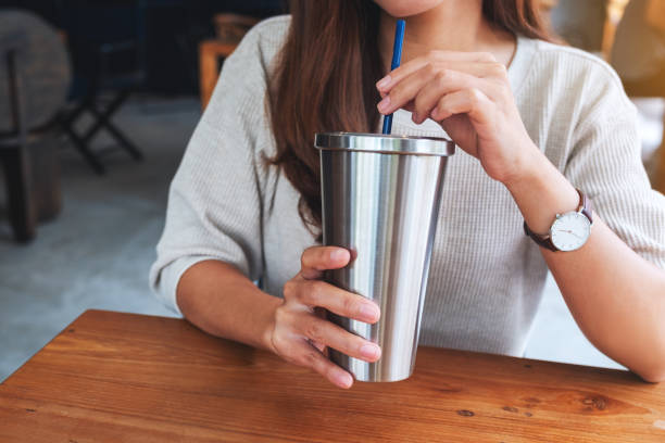 a woman drinking coffee in stainless steel cup Closeup image of a woman drinking coffee in stainless steel cup reusable cup straw stock pictures, royalty-free photos & images