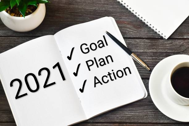 istock 2021 New Year. Goal,plan, action text on notepad with office accessories on a wooden background. Business motivation, inspection concepts ideas. 1280111256