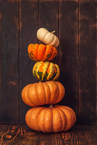Pyramid of pumpkins on a brown wooden background.