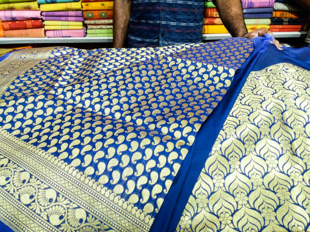 A seller displaying Indian sari in a clothing store A seller displaying Indian sari in a clothing store. Sari is the traditional dress of Indian women which can be of different types. It is made of yarn or silk. fashion bazaar stock pictures, royalty-free photos & images