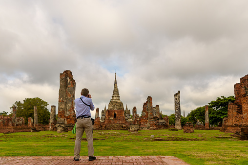 Westerner tourist is taking picture at the old Stupas in the ancient temple in Ayutthaya province, Travel in Thailand